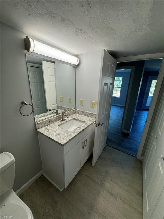 bathroom featuring hardwood / wood-style floors, vanity, a textured ceiling, and toilet