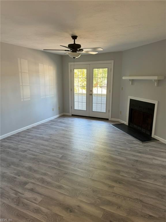 unfurnished living room with french doors, dark wood-type flooring, and ceiling fan