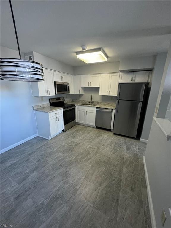 kitchen with white cabinets, stainless steel appliances, sink, and light stone counters