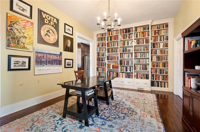 office space featuring built in shelves, a notable chandelier, dark hardwood / wood-style floors, and crown molding