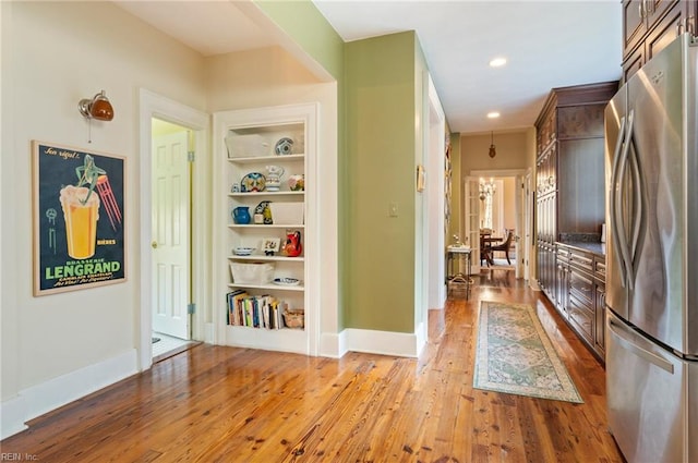 corridor with light hardwood / wood-style floors and built in features