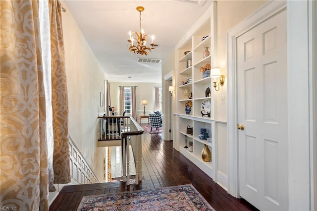 hall featuring dark wood-type flooring and a chandelier