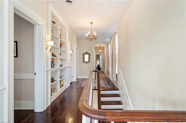 hallway with dark wood-type flooring and a notable chandelier