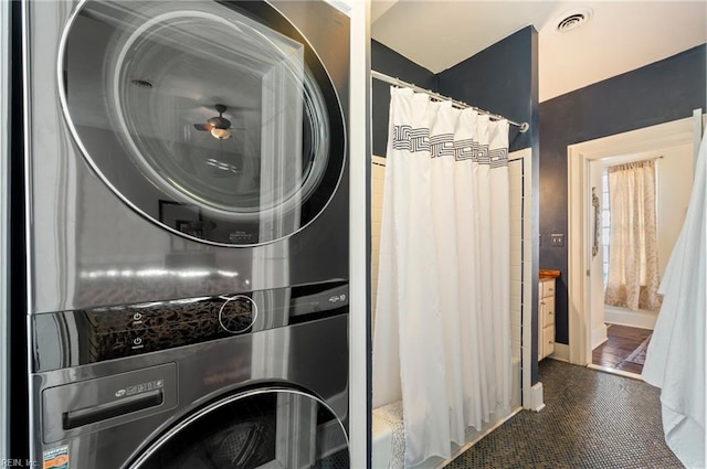 washroom with dark tile patterned floors and stacked washer / dryer