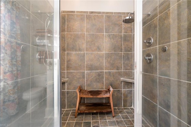 bathroom with toilet, tile walls, tile patterned flooring, and a tile shower