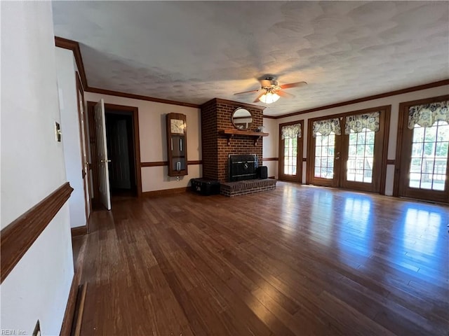 unfurnished living room featuring ceiling fan, dark hardwood / wood-style floors, crown molding, a brick fireplace, and french doors