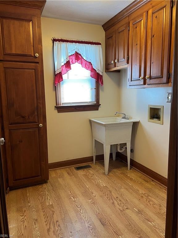 laundry room with cabinets, light hardwood / wood-style floors, and hookup for a washing machine