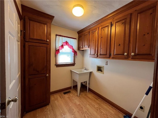 washroom with light hardwood / wood-style floors, hookup for a washing machine, and cabinets