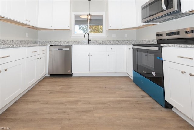 kitchen featuring light hardwood / wood-style flooring, sink, white cabinetry, appliances with stainless steel finishes, and decorative light fixtures