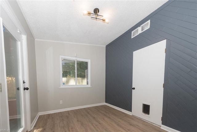 spare room with a textured ceiling, hardwood / wood-style flooring, and crown molding