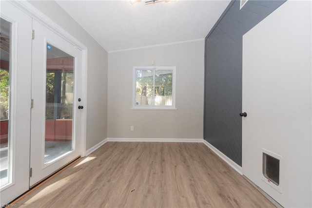 unfurnished room featuring ornamental molding, light wood-type flooring, and lofted ceiling