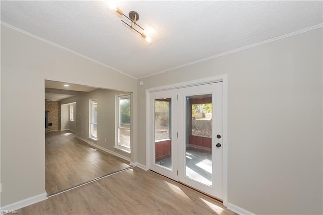 doorway to outside featuring ornamental molding, hardwood / wood-style floors, a fireplace, and vaulted ceiling