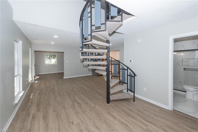 staircase with a textured ceiling and hardwood / wood-style flooring