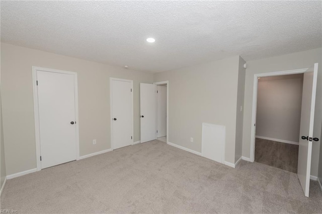 unfurnished bedroom featuring a textured ceiling and light carpet