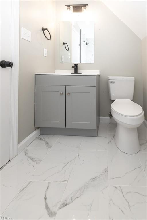 bathroom featuring vanity, toilet, and vaulted ceiling