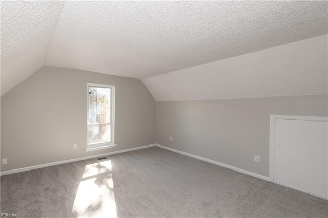 bonus room featuring vaulted ceiling, light carpet, and a textured ceiling