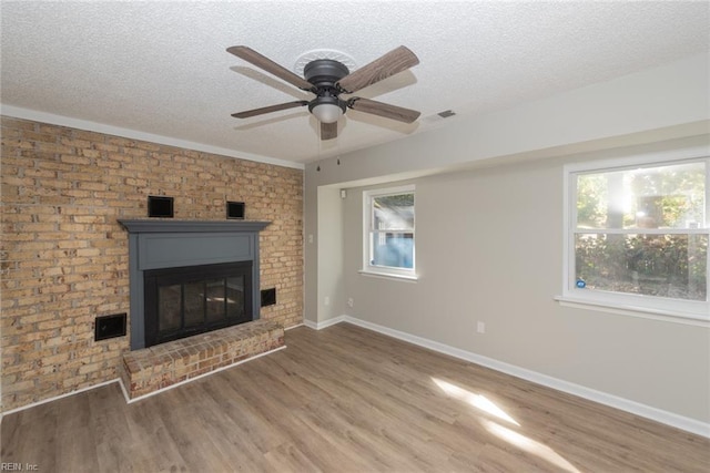 unfurnished living room with hardwood / wood-style floors, a wealth of natural light, ceiling fan, and a fireplace