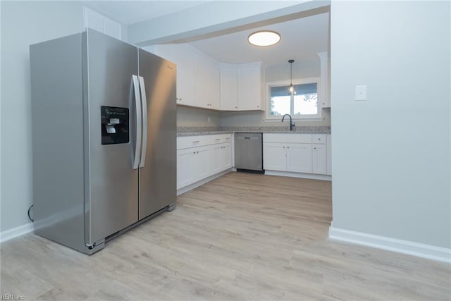 kitchen with stainless steel appliances, white cabinetry, pendant lighting, and light wood-type flooring