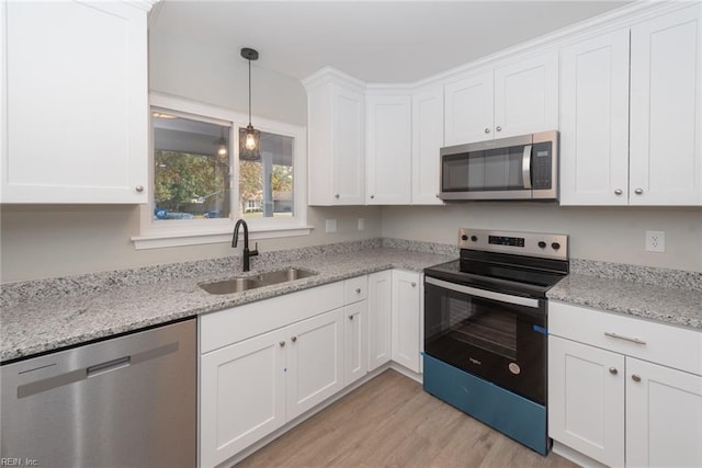 kitchen with stainless steel appliances, light hardwood / wood-style floors, sink, light stone counters, and white cabinets