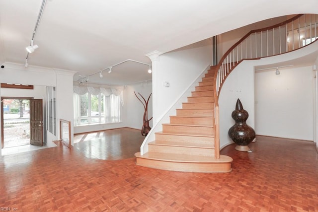 stairway featuring track lighting and parquet flooring