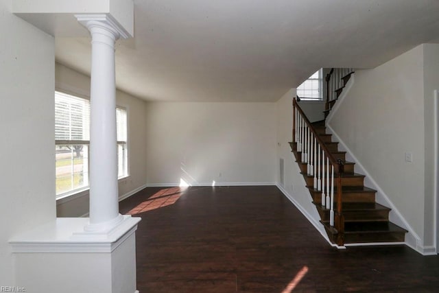 unfurnished living room featuring ornate columns and dark hardwood / wood-style flooring