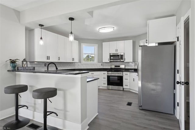 kitchen with kitchen peninsula, white cabinetry, pendant lighting, and appliances with stainless steel finishes