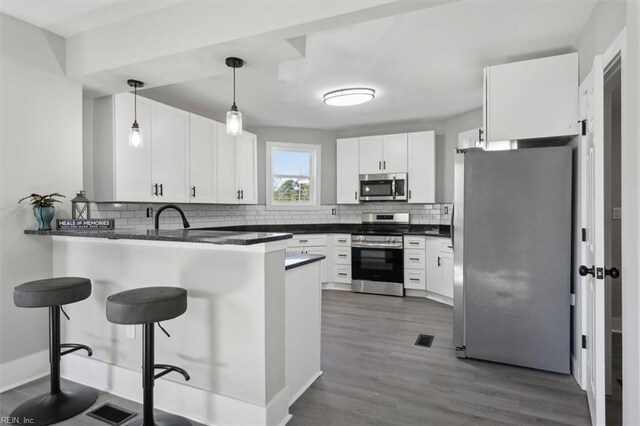 318 Sycamore Ave, Newport News, VA 23607 - kitchen featuring appliances with stainless steel finishes, a peninsula, tasteful backsplash, dark countertops, and a breakfast bar