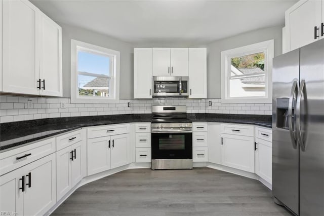 kitchen featuring stainless steel appliances, dark stone counters, dark hardwood / wood-style floors, backsplash, and white cabinets