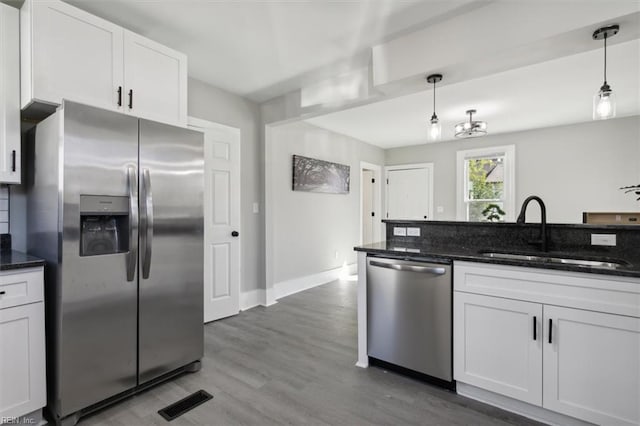 kitchen featuring hanging light fixtures, white cabinets, sink, and stainless steel appliances