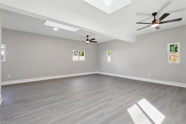 unfurnished room featuring a skylight, hardwood / wood-style floors, and ceiling fan