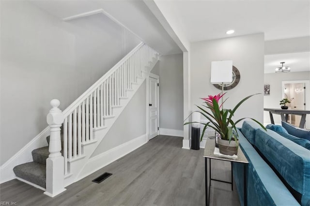 stairway with hardwood / wood-style floors and a notable chandelier