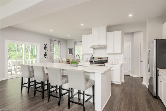 kitchen with a kitchen breakfast bar, white cabinetry, stainless steel appliances, and a kitchen island with sink