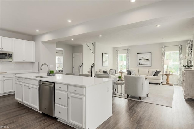 kitchen with stainless steel appliances, white cabinetry, a kitchen island with sink, and a healthy amount of sunlight