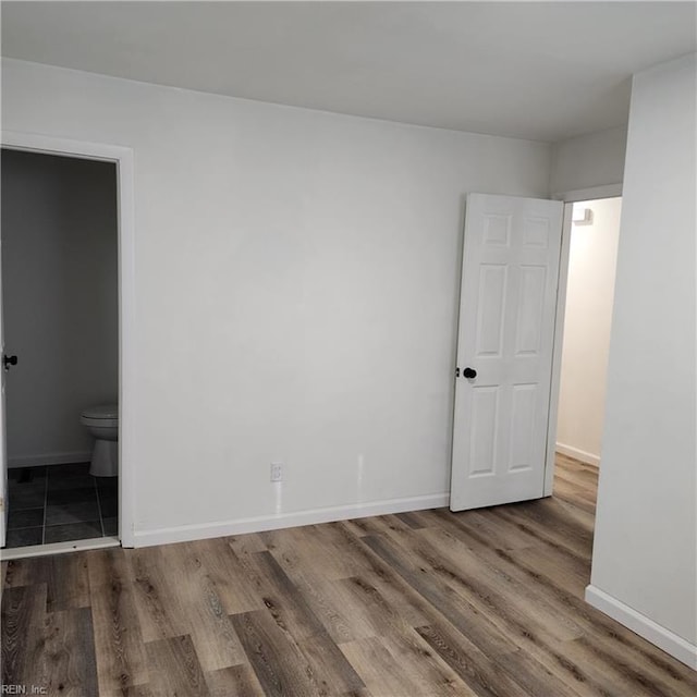 unfurnished bedroom featuring hardwood / wood-style flooring and ensuite bath