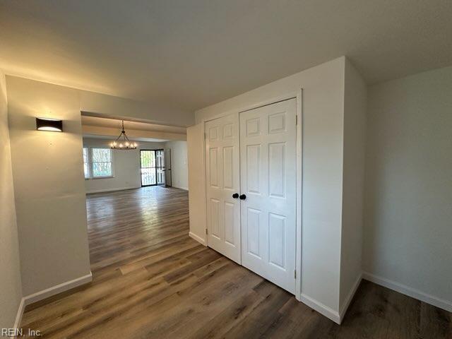 corridor with dark hardwood / wood-style flooring and an inviting chandelier