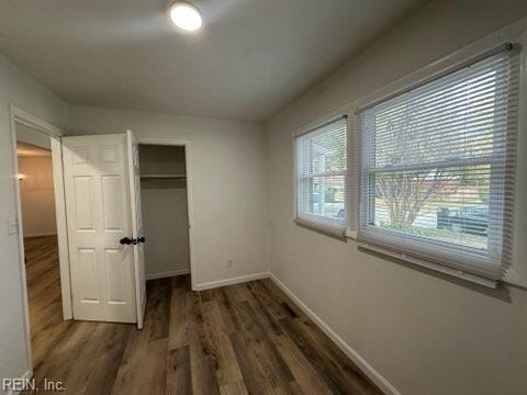 unfurnished bedroom featuring multiple windows, a closet, and dark hardwood / wood-style floors