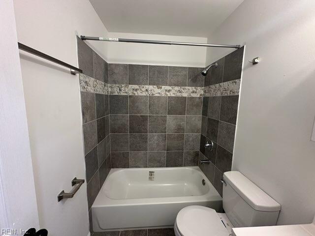 bathroom with toilet and tiled shower / bath