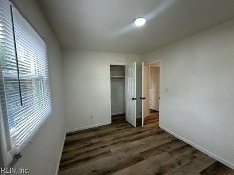 unfurnished bedroom with dark hardwood / wood-style flooring and a closet