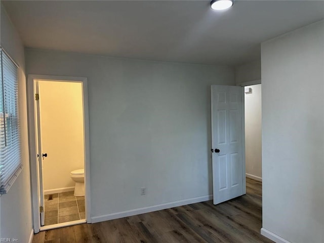 unfurnished bedroom featuring ensuite bath and dark hardwood / wood-style floors