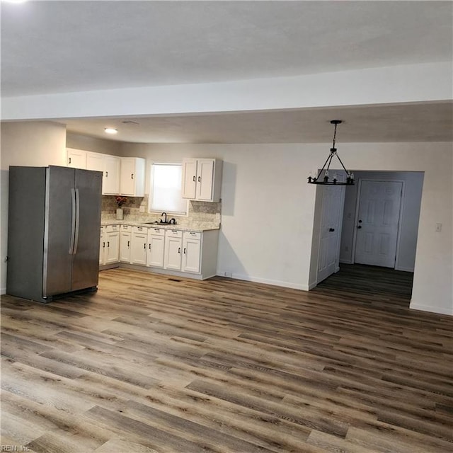 kitchen featuring white cabinets, hanging light fixtures, sink, dark hardwood / wood-style flooring, and stainless steel refrigerator