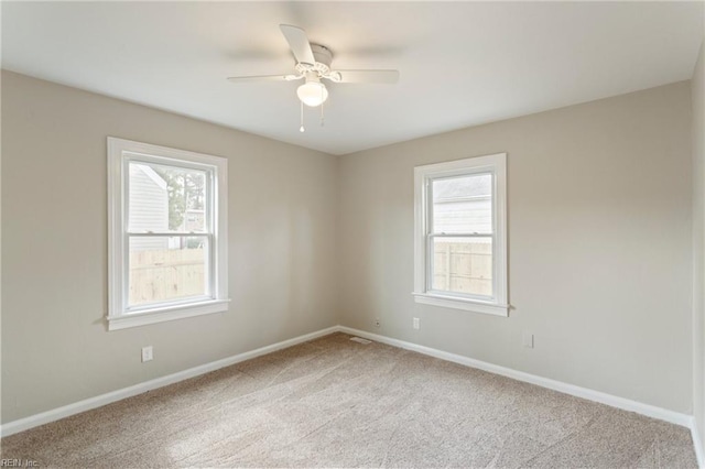 empty room with ceiling fan, light colored carpet, and a healthy amount of sunlight