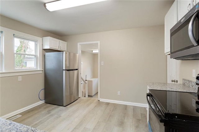 kitchen featuring stainless steel appliances, light stone countertops, light hardwood / wood-style flooring, and white cabinets