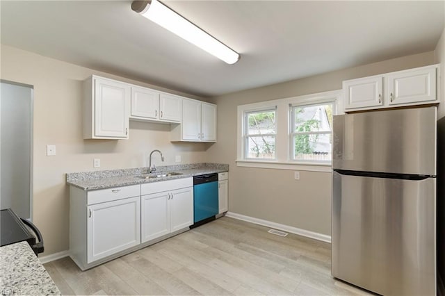 kitchen featuring sink, white cabinetry, stainless steel appliances, light stone counters, and light hardwood / wood-style floors