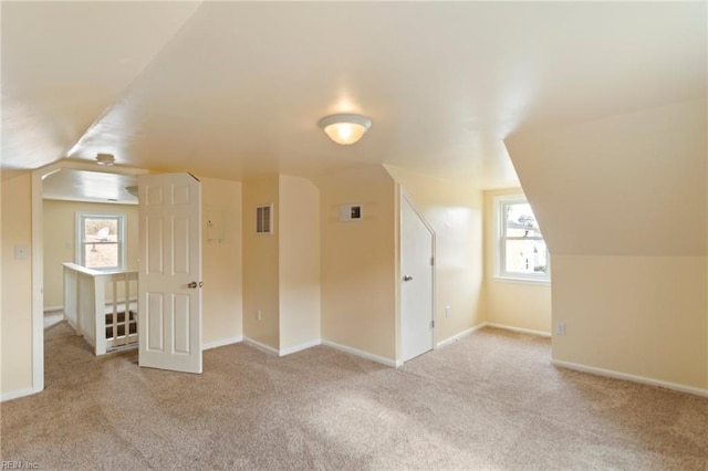 additional living space featuring lofted ceiling and light carpet