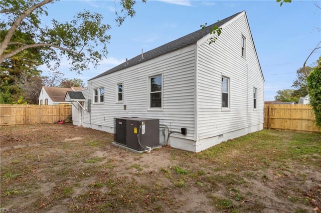 rear view of house with central AC and a lawn