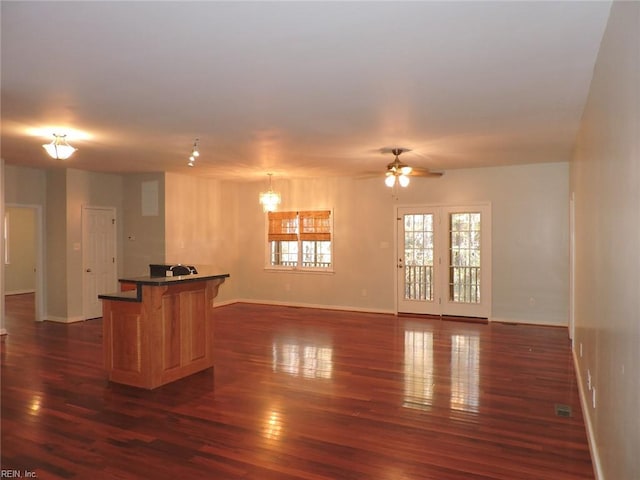 interior space with ceiling fan with notable chandelier, dark wood-type flooring, a center island, and a breakfast bar