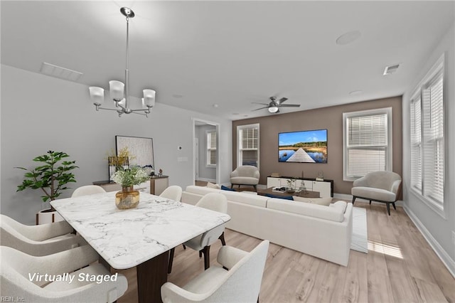 dining room featuring light hardwood / wood-style floors and ceiling fan with notable chandelier