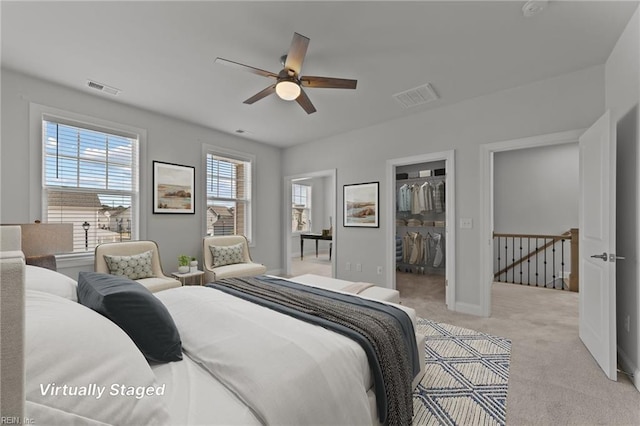 bedroom with a closet, a walk in closet, light carpet, and ceiling fan