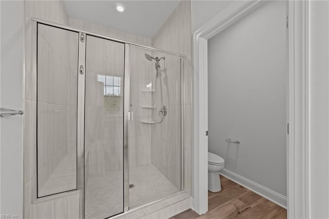 bathroom featuring wood-type flooring, toilet, and an enclosed shower