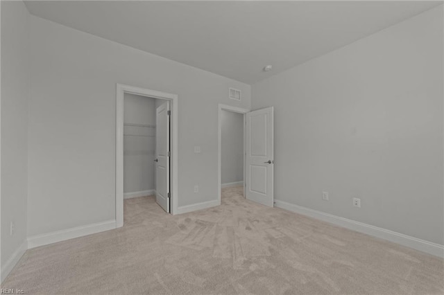 unfurnished bedroom with a closet, a spacious closet, and light colored carpet